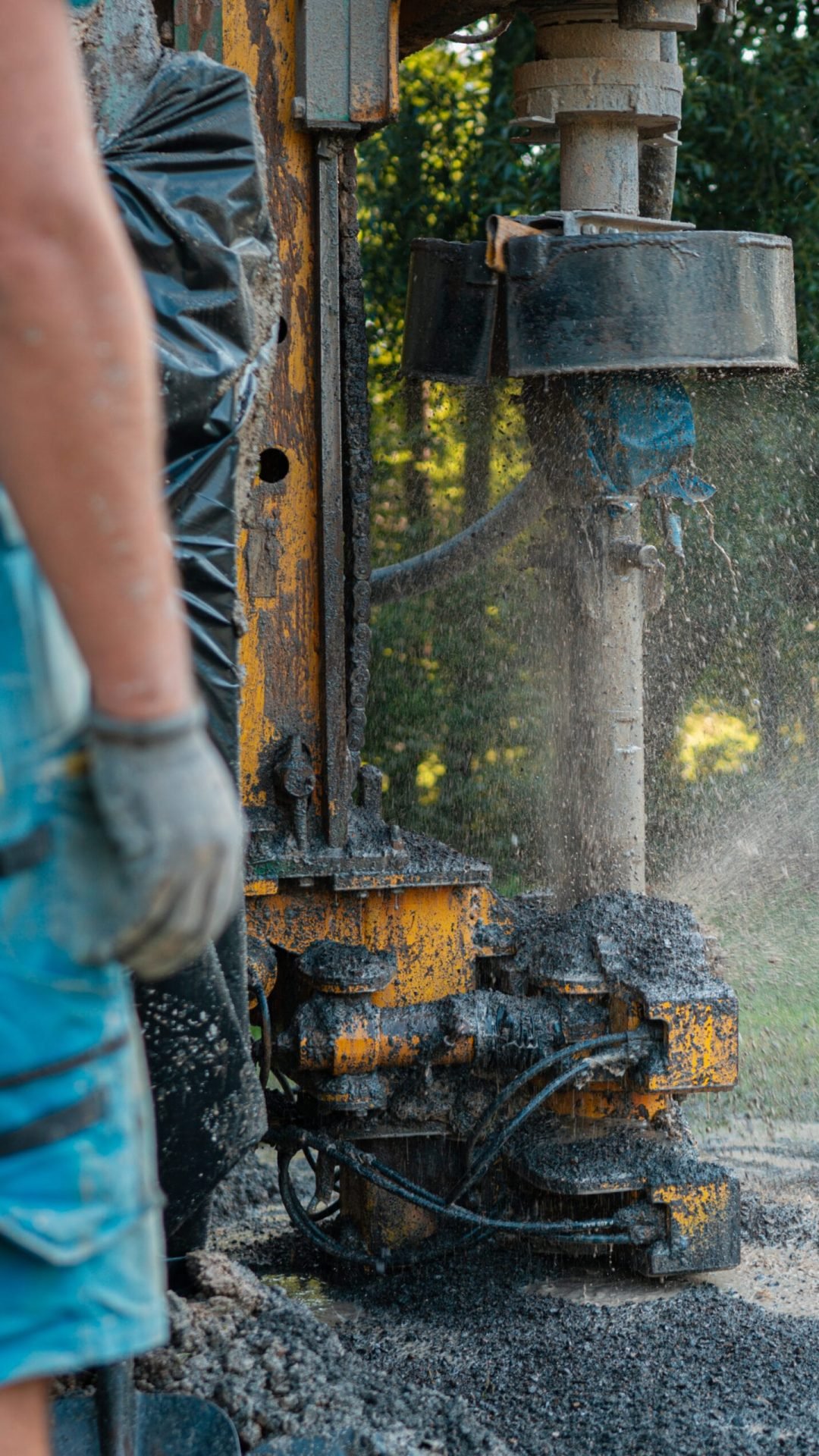 Close up of well drilling rig boring dowin into the earth. Close up of well drilling rig boring dowin into the earth. A rotary drill rig using bits to bore into ground and loosing the soil and rocks. Drilling equipment using water to cool down bits. Professional worker looking at working machine. Mud and muddy water is spitting out when drilling borewell. Banner with copy space.